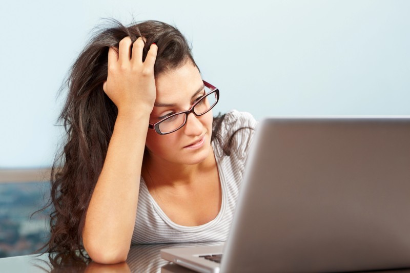 Photo of a woman looking at a computer screen, clearly not happy with what she sees