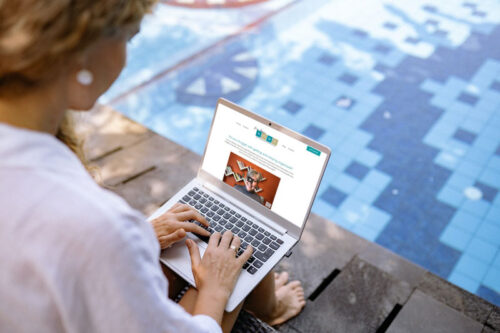woman viewing a website on a laptop by the pool